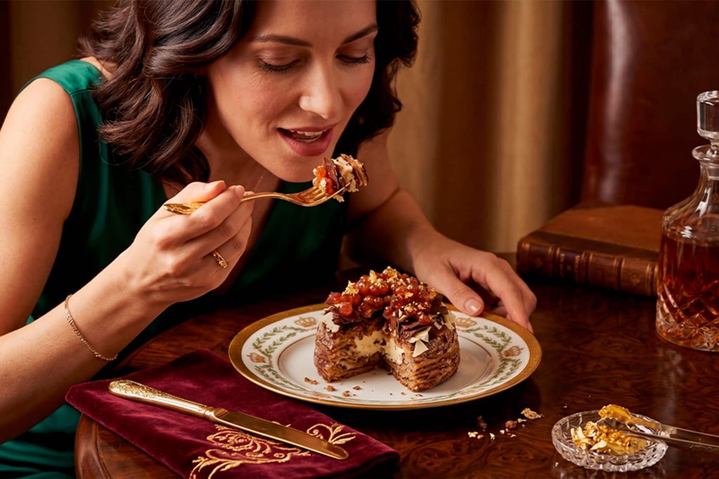 Woman enjoying a luxury chocolate donut topped with gold flakes for National Donut Day.