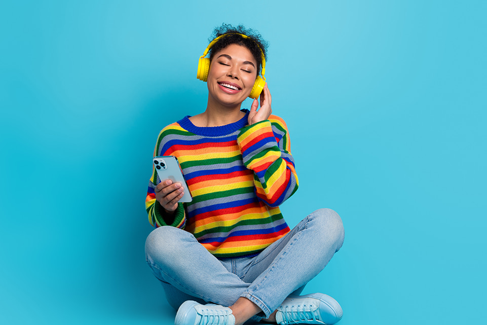 Person wearing a rainbow sweater against a blue background for an article about lucky colors and lottery luck.