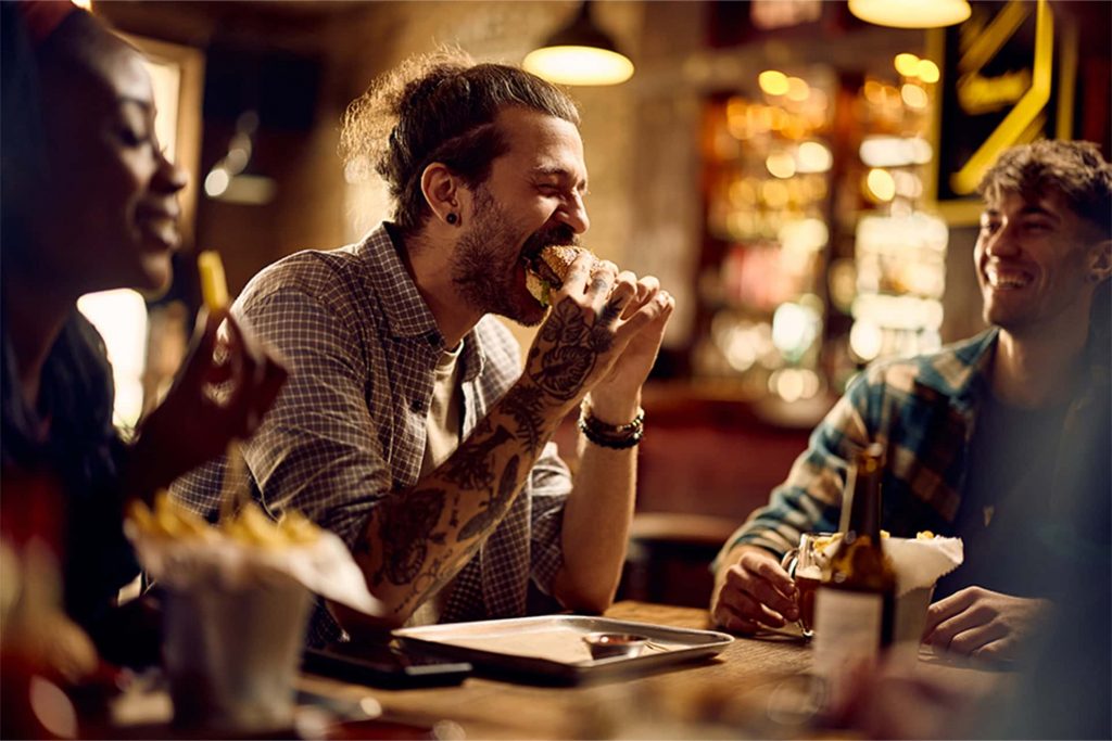 Man enjoying a burger at a casual restaurant for National Hamburger Day