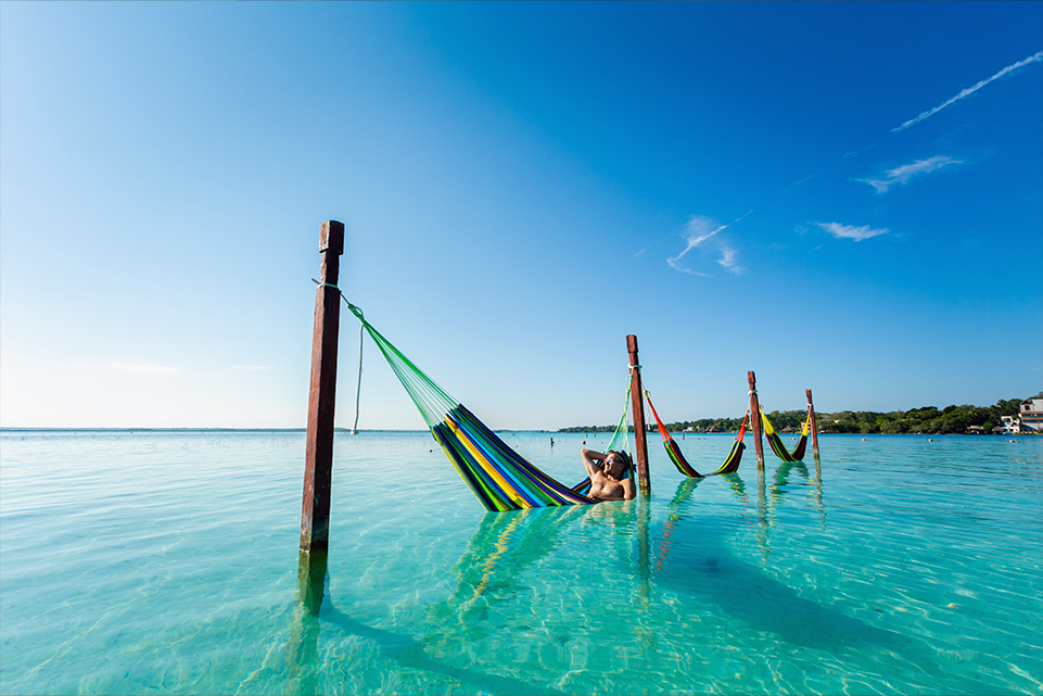 Subscribe to Mega Millions while relaxing in a hammock over turquoise water on summer vacation.