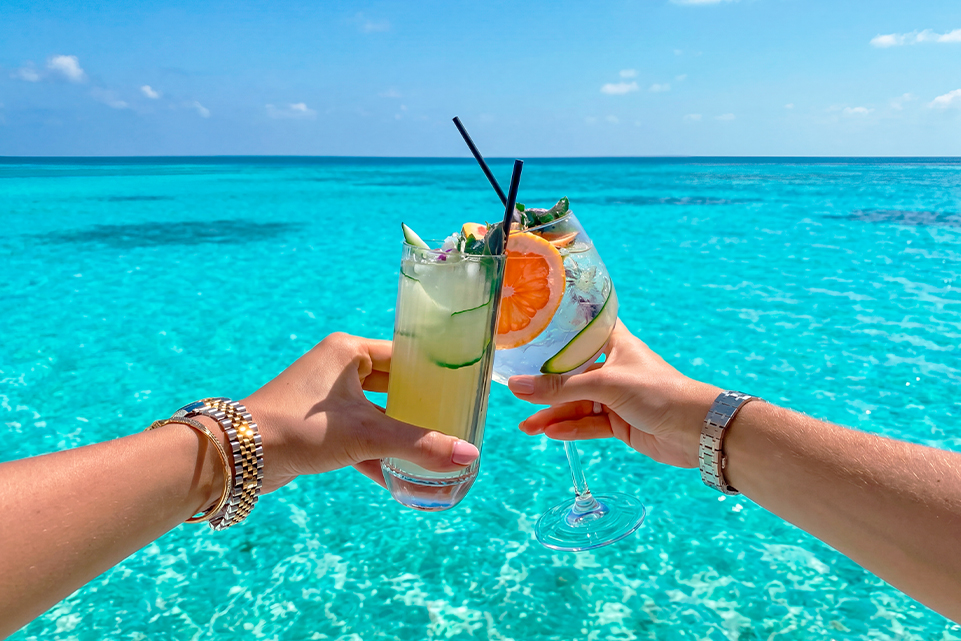 Two people raising tropical cocktails on a beach, inspired by Powerball dream trips