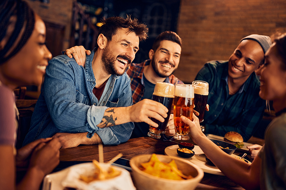 Friends raising glasses of beer around a table on International Beer Day